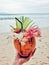 Ginger coconut with white and pink flowers, a black straw and a palm tree leafe