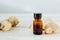 Ginger essential oil in glass bottle with ginger root behind.