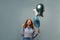 Ginger excite woman pointing finger upward while posing with balloons