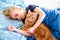 Ginger fluffy cat with little sleeping girl on the blue bed