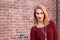 Ginger grungy woman and a brick wall. Fashion photo