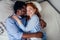 Ginger hair european female and handsome afro african male together hugging lying in bedroom at home cozy apartment