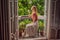 A ginger-haired woman stands on a heritage-style balcony enjoying her morning coffee. A woman in a hotel in Europe or