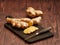 Ginger root, slices of ginger root and a knife on a burned wood cutting board