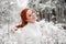 Ginger smiling female in white sweater in winter forest. Snow december in park. Portrait. Christmas cute time.