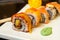 Ginger sushi rolls with decorations and sushi sticks served on a white tray