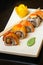 Ginger sushi rolls with decorations and sushi sticks served on a white tray