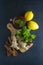 Ginger tea cup with lemons and mint leaves on dark background. Ginger tea, drink ingredients, cold and autumn time