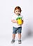 Ginger toddler in white t-shirt denim shorts. Drinking cocktail from plastic bottle in form of pineapple, posing isolated on white