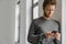 Ginger young man using mobile phone while leaning on wall