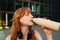 Ginger young woman with headphones drinking water after workout