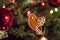 Gingerbread bird hang on the christmas tree with light garland and glass spheres