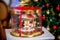 Gingerbread carousel in a gift box in front of defocused lights of Chrismtas decorated fir tree. Holiday sweets. New Year and Chri