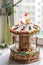 A gingerbread carousel and some Christmas decoration elements on a white wooden surface