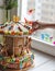 A gingerbread carousel and some Christmas decoration elements on a white wooden surface