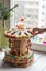 A gingerbread carousel and some Christmas decoration elements on a white wooden surface