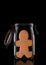 A Gingerbread Man in a glass storage or canning jar isolated on black with reflection, with lid open
