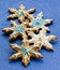 Gingerbread shaped snowflakes decorated with icing and sugar sprinkling on solid blue background