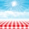 Gingham picnic table against blue cloudy sky