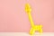 Giraffe figure made of modelling balloon on table against color background.