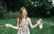Girl 10 years old in a dress holding shoes in her hands and laughing in a clearing in nature rejoicing in nature
