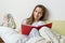 Girl 10 years old sitting at home in bed with a school notebook, reading and learning, preparing for school at home