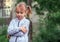 Girl 5 years old, blonde, stands in the yard with an offended expression on her face