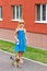 Girl 6 years old in blue dress walking with a Yorkshire terrier near high-rise building