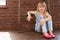 Girl 6 years old sits on the floor next to a brick wall and filled with laughter