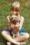 Girl 6 years old sitting on the grass and holds Yorkshire Terrier