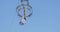 Girl acrobat in white dress in the air above the street in a big chandelier on the rope