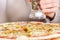 Girl adding spices on top of pizza