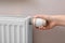 Girl adjusting heating radiator thermostat near white wall, closeup