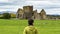 Girl admiring the ruins of a castle situated near a lake in Ireland highlands