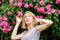 Girl adorable blonde sniffing fragrance of pink bloom. Spring and summer. Perfume and cosmetics. Woman in front of