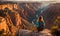 Girl in adventure attire stands at cliff edge, overlooking vast canyon