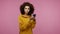 Girl afro hairstyle in hoodie scrolling social network using mobile phone and looking at camera surprised