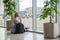 Girl at the airport near window is waiting for a flight with luggage backpack and looking at a plane