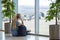 Girl at the airport near window is waiting for a flight with luggage backpack and looking at a plane