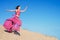 Girl in airy crimson dress running on sand dunes