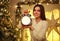 Girl with alarm clock at home in Christmas decorations