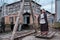 A girl in an ancient dress swings on her feet on a swing. Old town with abandoned houses