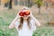 Girl with Apple holding in front of her face in park. Beautiful Girl Eating Organic Apple in the Orchard. Harvest Concept. Garden