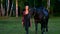 Girl approaches camera leading horse under bridle