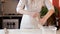 The girl in the apron puts the remains of raw dough in a plastic container