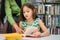 Girl ask for teacher to answer question in book while reading book at school library. Education and learning concept