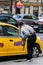 Girl asking taxi driver if available for a ride. Taxi car parked at the taxi station in the capital city of Bucharest, Romania,