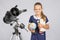 Girl astronomer is a telescope with a globe and books in the hands