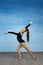 Girl athlete doing exercise gymnastics, looking at the camera on a blue background.