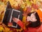 Girl in autumn orange foliage with laptop.